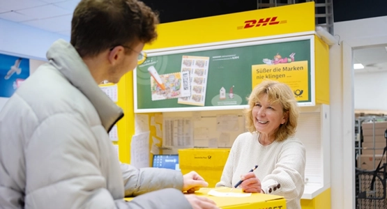 Eine Frau am Postschalter von DHL bedient einen Kunden
