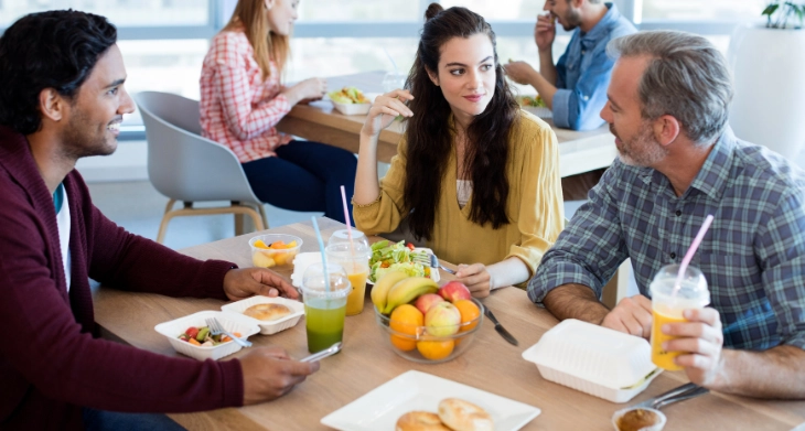 Kollegen essen gemeinsam in der Pause am Tisch