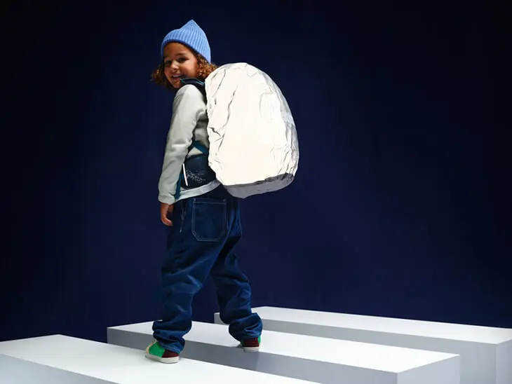 Ein Kind trägt einen Schulranzen von ergobag mit einer vollreflektierenden Regenhülle