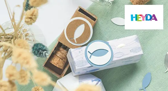 Verschiedene gebastelte Karten mit Produkten von HEYDA liegen auf einem blauen Untergrund.