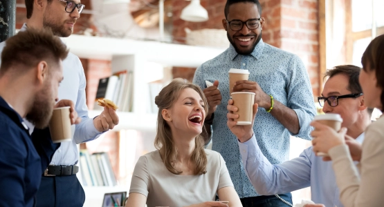 Kollegen genießen gemeinsam Kaffee und lachen im Büro.