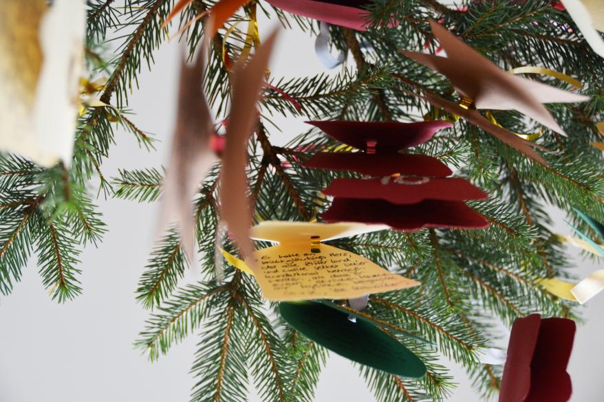 An einem Ast hängen gebastelte Anhänger mit Sprüchen. 