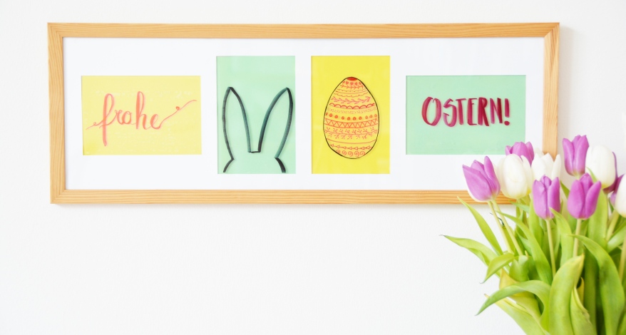 Bilderrahmen mit Ostermotiven. Davor Tulpen-Blumenstrauß