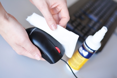 Eine PC-Maus wird mit einem Vliestuch gesäubert.
