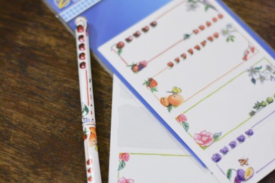 Etiketten mit Obst-Aufklebern der Marke Avery Zweckform liegen auf einem Tisch. Daneben liegt ein Holzstab, der mit den Obst-Aufklebern beklebt ist.