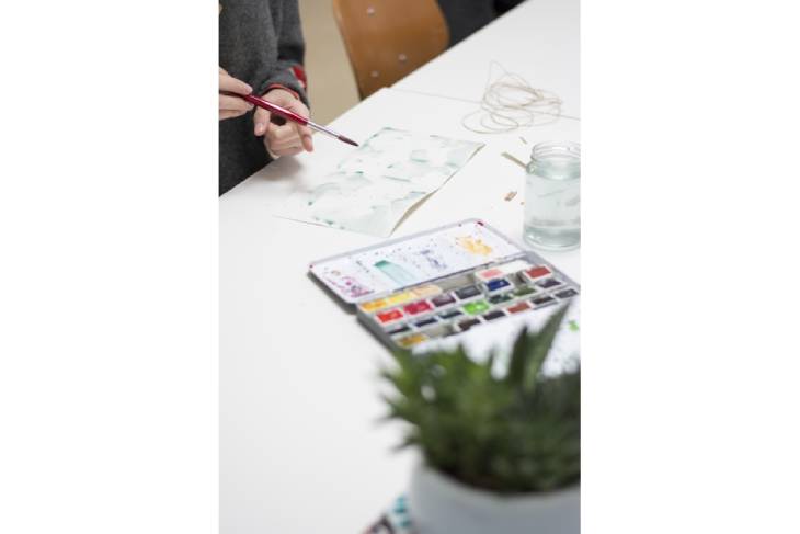 Bastelmaterial und Aquarellfarben auf Tisch mit DIY-Karte