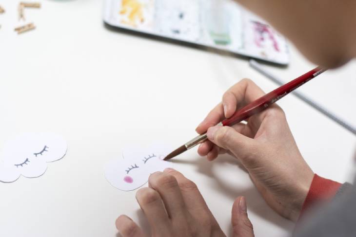 Wolken wird liebevoll mit Pinsel ein Gesicht aufgemalt