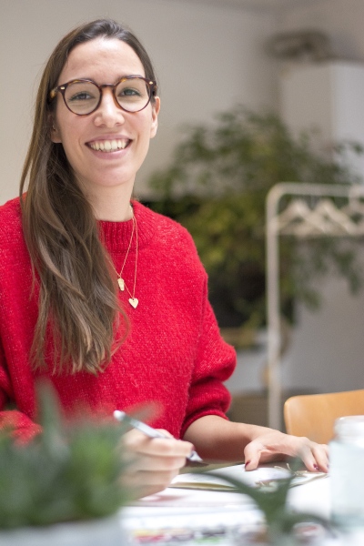 Yasmin von May & Berry beim Basteln am Tisch und lächelt in die Kamera