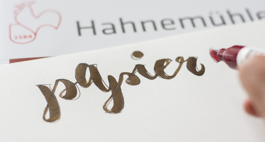 Wort 'papier' wird mit Brushpen auf Hahnemühle-Papier geschrieben.