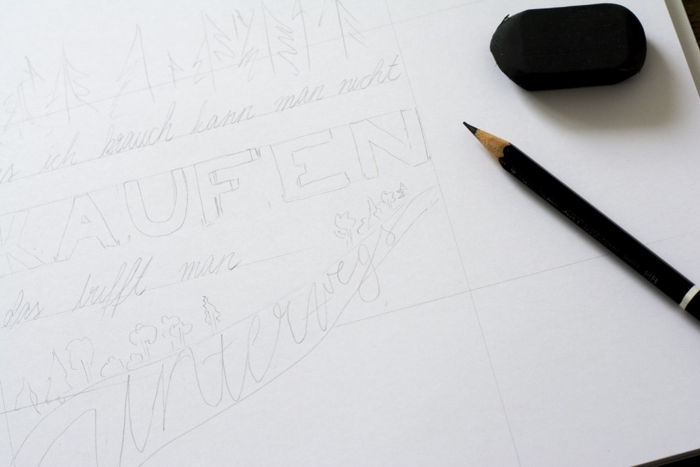 Skizze mit Lettering-Entwurf, Bleistift und schwarzem Radiergummi