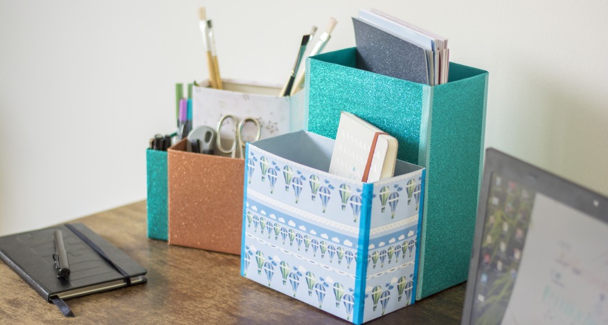 Zwei Organizer aus Müslikartons stehen auf einem Schreibtisch. Sie wurden mit Washitape dekoriert und sind mit Büromaterial gefüllt.