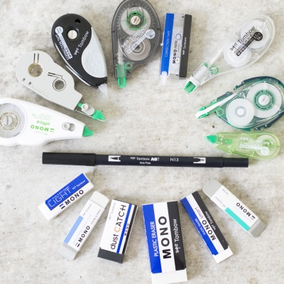 Verschiedene Korrekturroller, Radierer und Brushpen im Kreis angeordnet