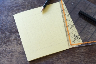 Gelbes Papier mit vorgezeichnetem Gitterraster und Lineal