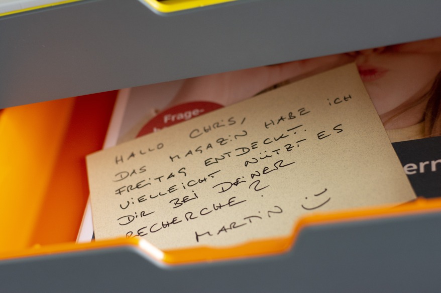 Persönliche Nachricht auf Zettel im orangefarbenen Ablagefach