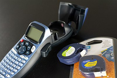 Offenes Beschriftungsgerät mit zwei Etikettenkassetten auf schwarzem Untergrund.