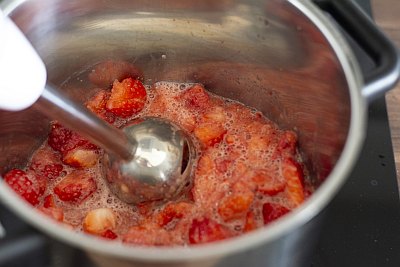 Erdbeeren werden mit Pürierstab in einem Topf verarbeitet.