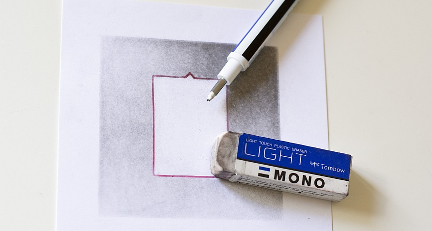 Ein Radierer und ein weißer Marker liegen auf einem Papier, auf dem die Radiertechnik angewendet wurde.