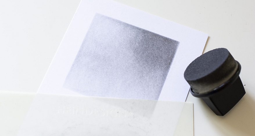 Farbverlauf von Graphit mit Radiertechnik auf einem Papier, daneben liegt ein Schwämmchen.