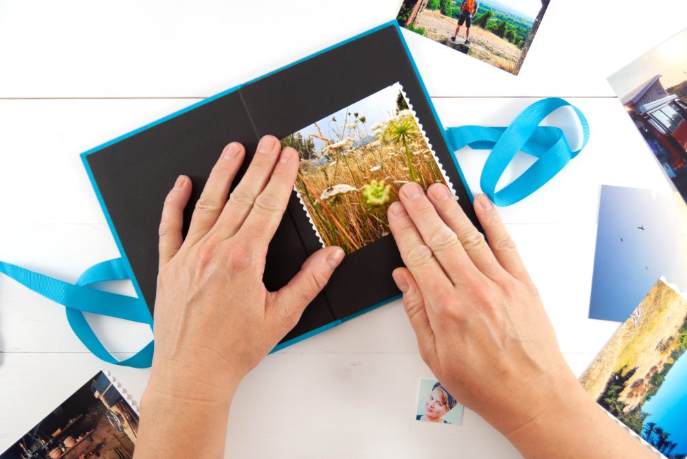 Hände kleben Foto in blaues Leporello-Album.