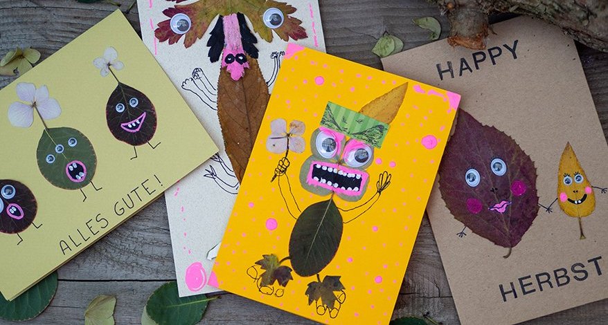 Selbst gebastelte Herbstkarte mit Blättern mit Gesichtern und auf Holztisch