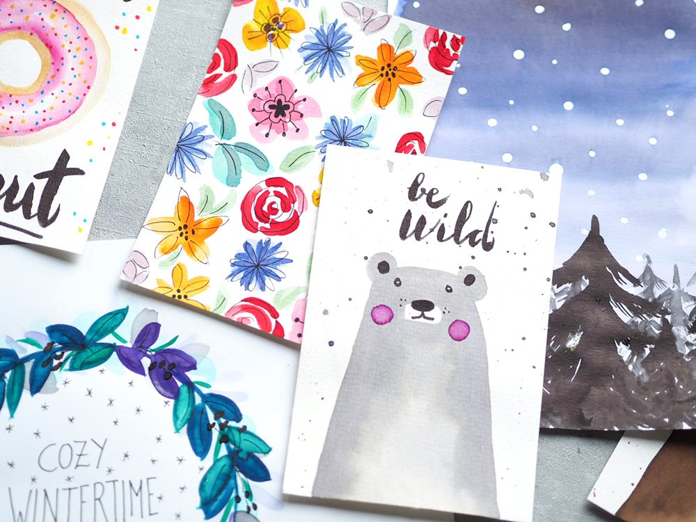 Verschiedene Aquarell-Postkarten mit floralen und winterlichen Motiven.
