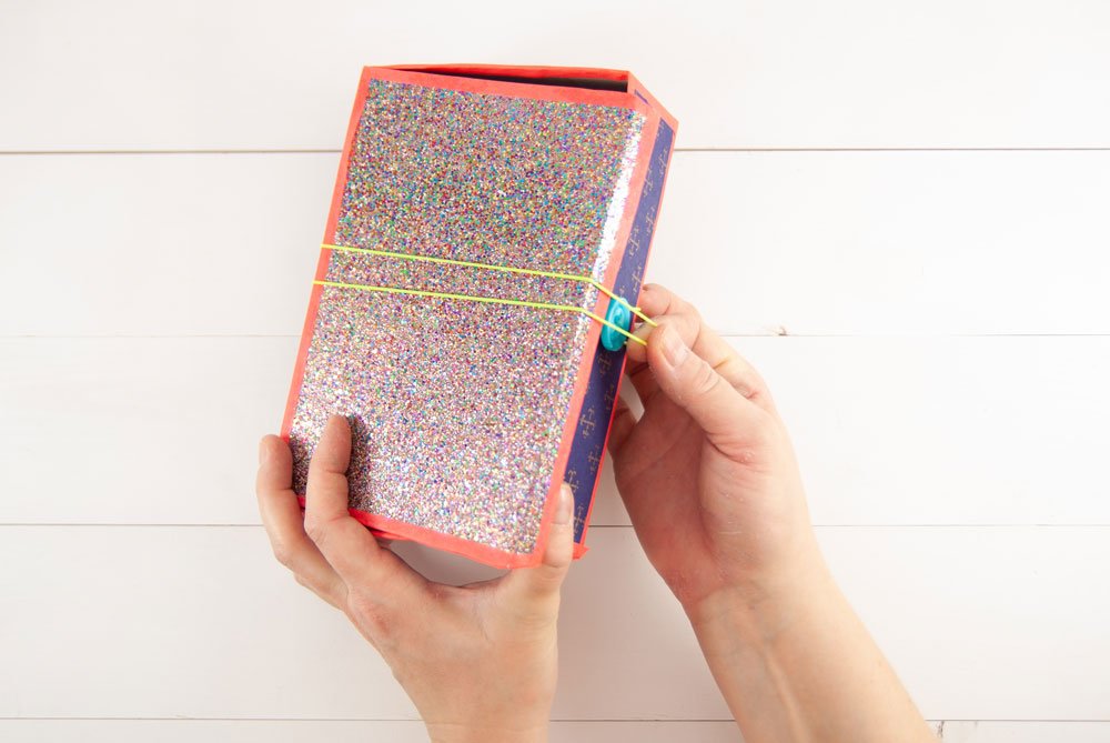 Fertige DIY-Box mit Glitzerdeckel wird mit Gummiband verschlossen