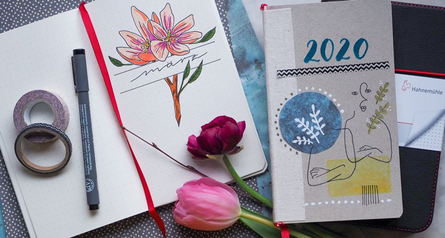 Notizbuch mit Märzzeichnung und Kalender 2020 neben Tulpen