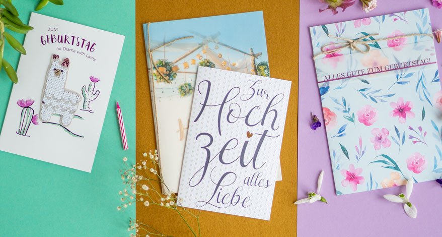 Unterschiedliche Geburtstags- und Hochzeitskarten liegen auf einem bunten Untergrund.