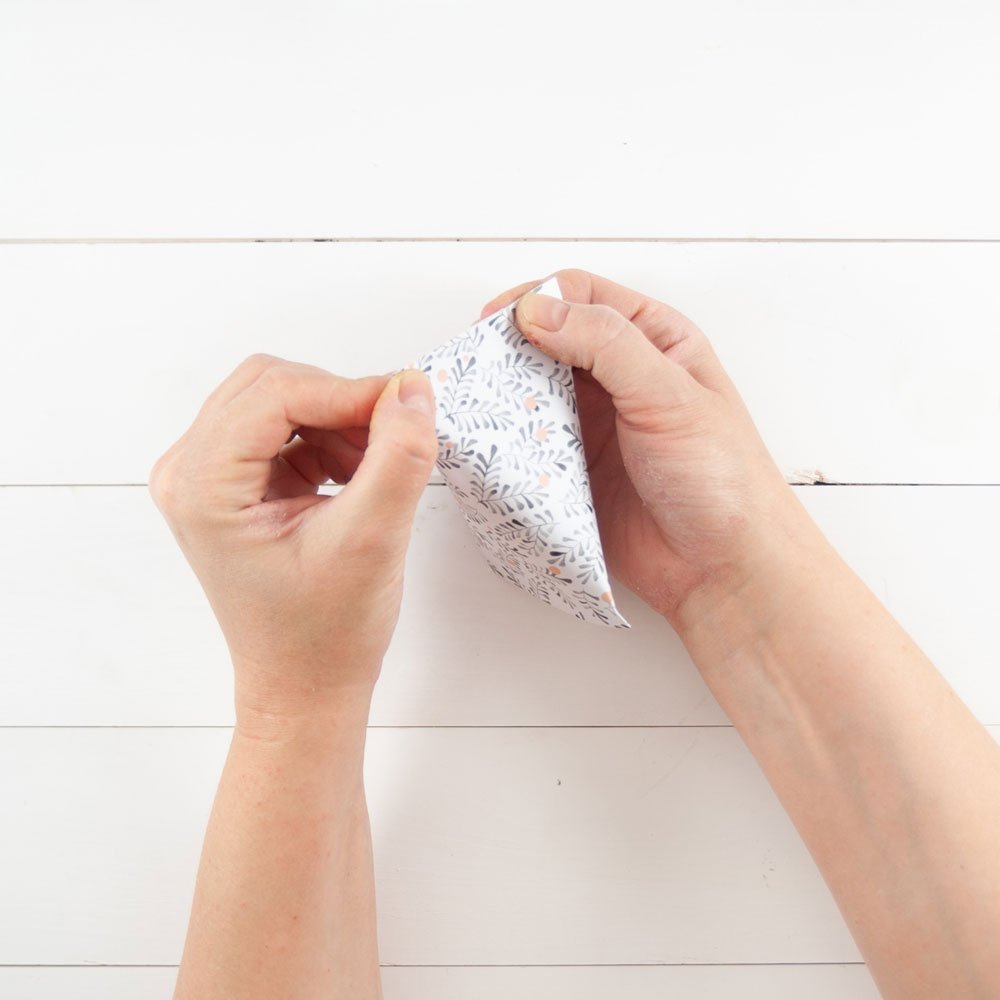 Zwei Hände drücken die kurze Seite der Papierrolle zusammen.