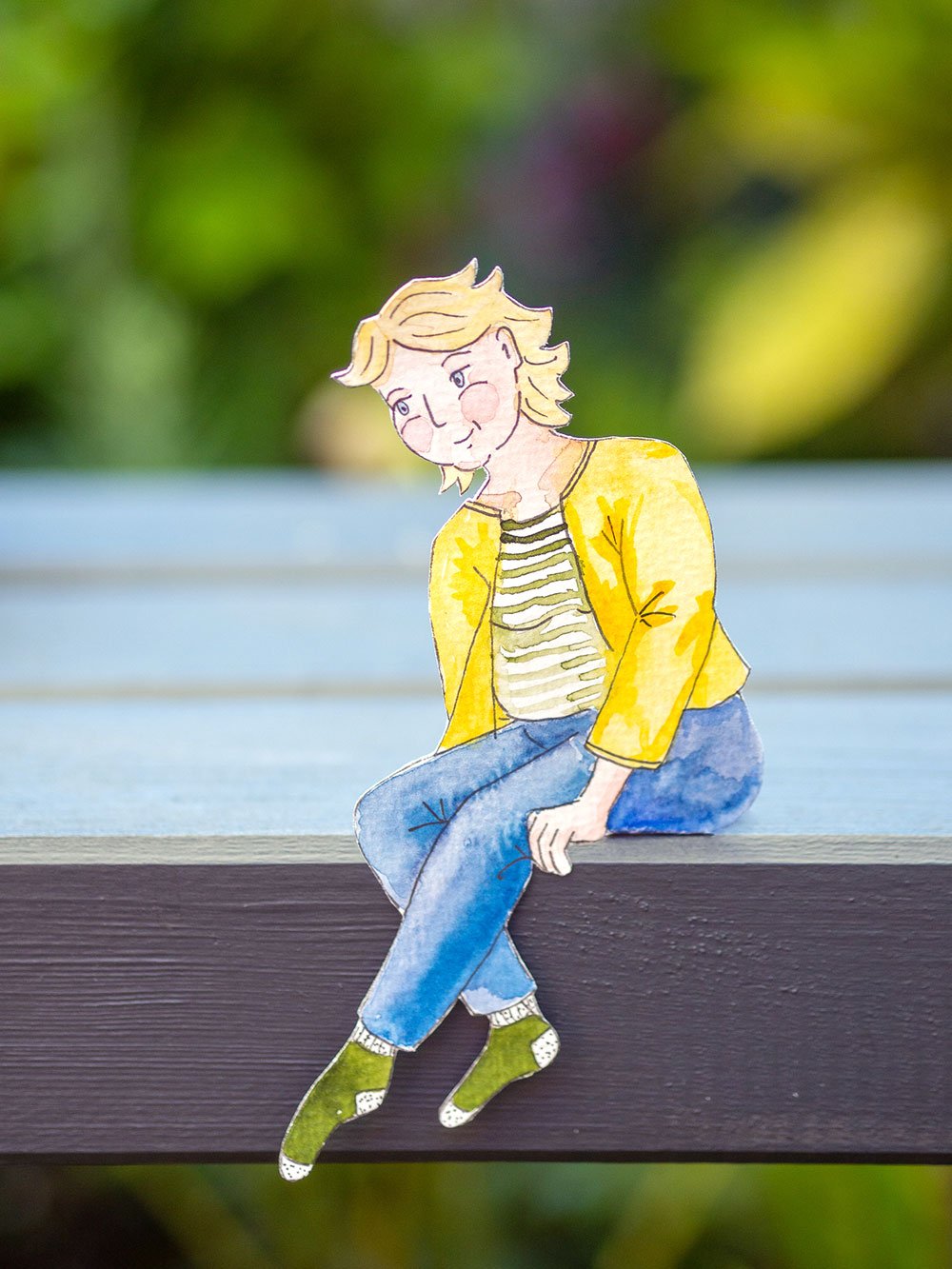 Illustrierte Figur einer Frau, aus Papier ausgeschnitten, aufgestellt auf einen Holzbalken