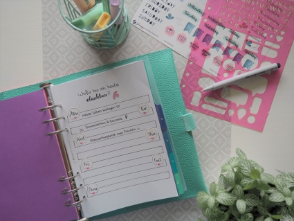 Geöffneter Filofax Planner mit "Feel-Good-Liste", pinker Schablone und Stift