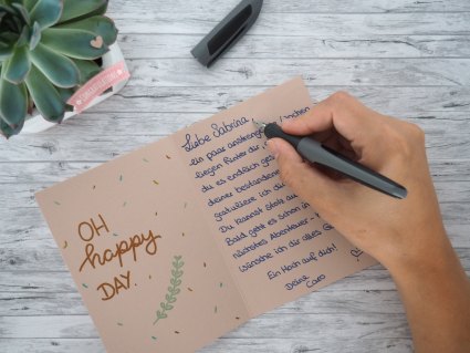 Jemand schreibt mit Füller eine Karte