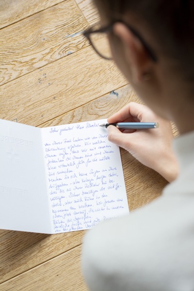Eine Frau Schreibt eine Gute Besserung Karte mit einem Füller.