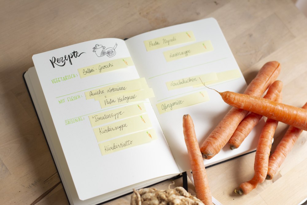 Bullet Journal mit Rezeptideen und Karotten auf Holztisch