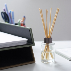 Nahaufnahme von Schreibtisch: Duftstäbchen stehen im Homeoffice neben Ablageschale und Stifteköcher aus der S.O.H.O.-Serie von Rössler.
