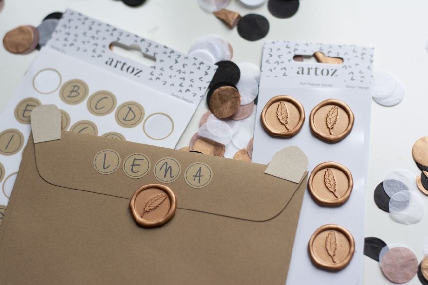 Rückseite eines Briefumschlags ist mit Buchstabenaufklebern und dem Namen Lena beschriftet. Ein Siegelsticker verschließt den Umschlag.