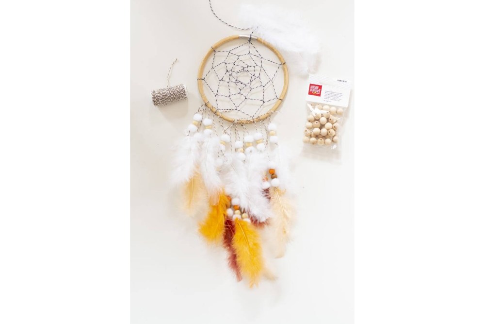 Bastelanleitung Do it yourself-Traumfänger für Kinder basteln. Schritt 3: eine zweite Reihe Federn, Pompons und Holzperlen auffädeln und an den Holzring knoten.