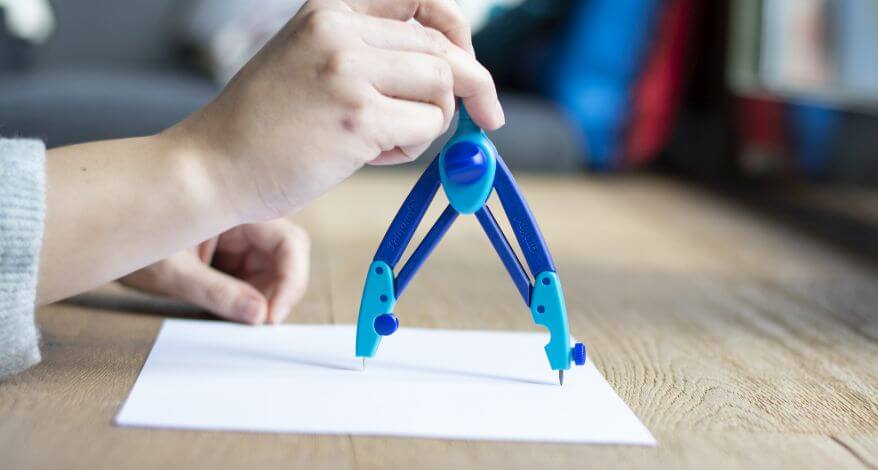 Seitlicher Blick auf eine Hand, die den Schulzirkel Griffix von Pelikan auf ein Blatt Papier aufsetzt, um einen Kreis zu zeichnen.