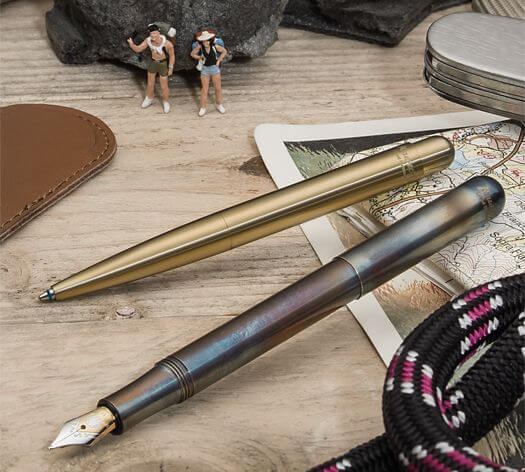 Ein Füllhalter und ein Kugelschreiber der Serie Liliput von Kaweco liegen dekorativ auf einem Schreibtisch. 