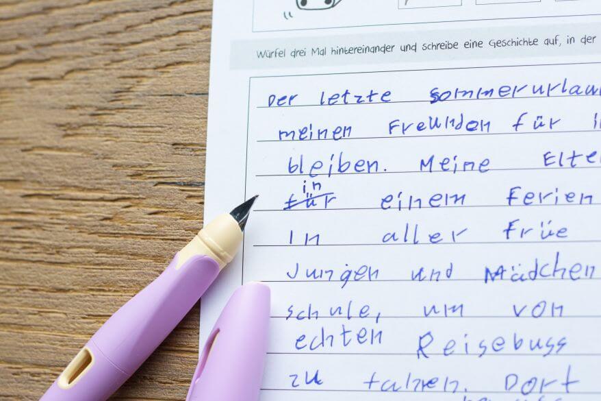 Nahaufnahme des Schreiblernfüllers Easybirdy von Stabilo, der neben den Aufsatz eines Grundschülers liegt.