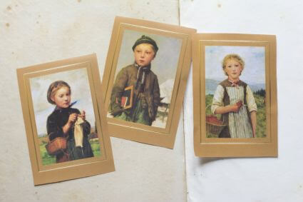 Ansicht von drei historischen Postkarten mit gemalten Kindermotiven von Albert Anker.