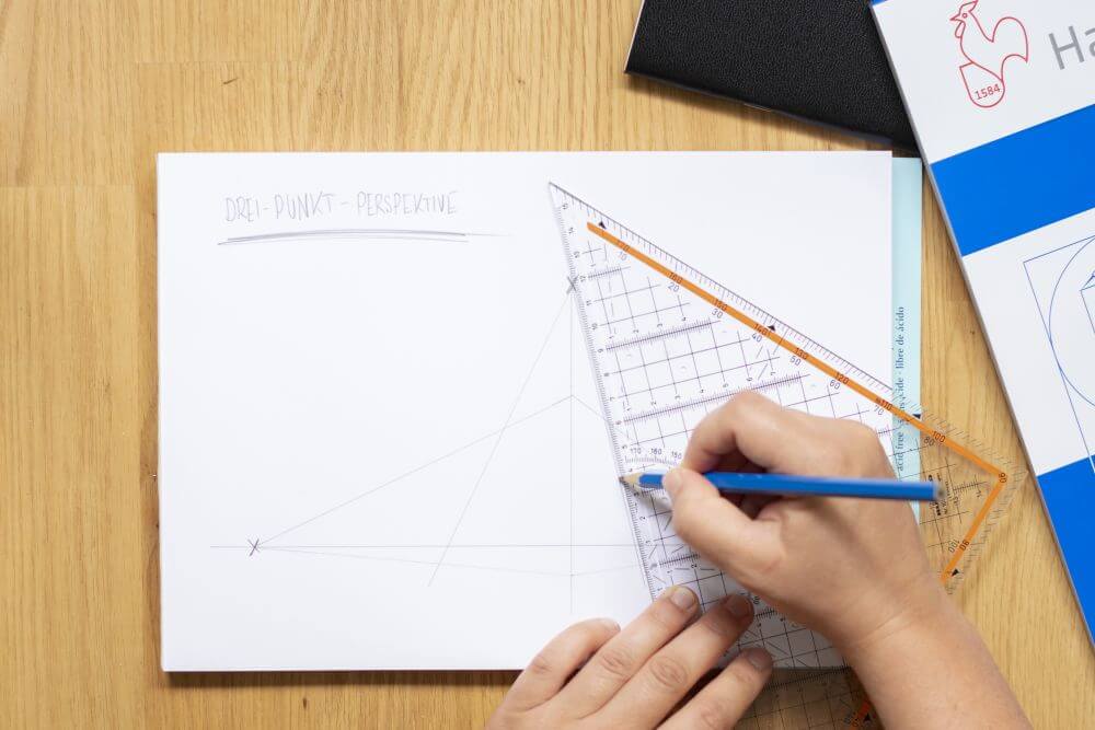 3-Punkt-Perspektive Schritt 5: Vom Fluchtpunkt der vertikalen Hilfslinie aus zwei Fluchtlinien schräg nach unten ziehen, welche die bereits gezeichneten Fluchtlinien schneiden.