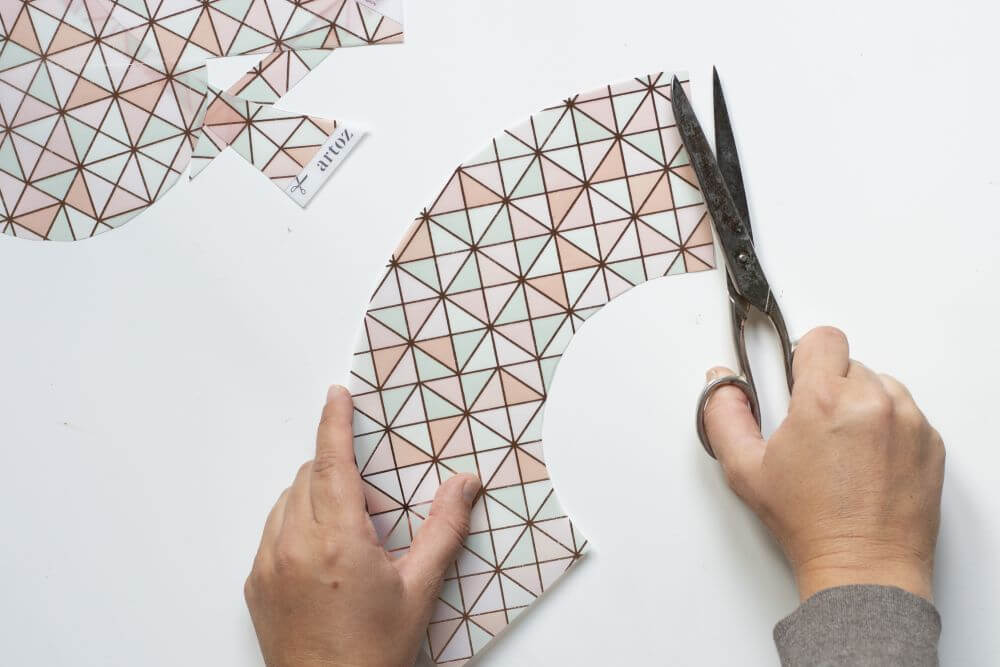 Eine Person schneidet einen Halbkreis aus buntem Transparentapier aus.