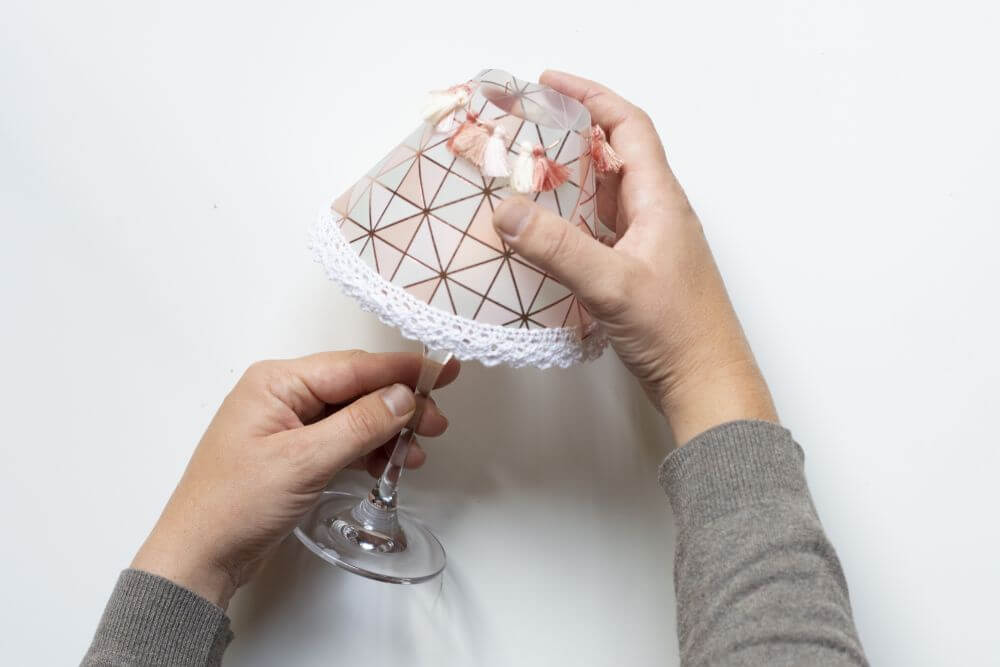 Ein selbstgebastelter Lampenschirm aus buntem Transparentpapier wird über wein Weinglas gestülpt.