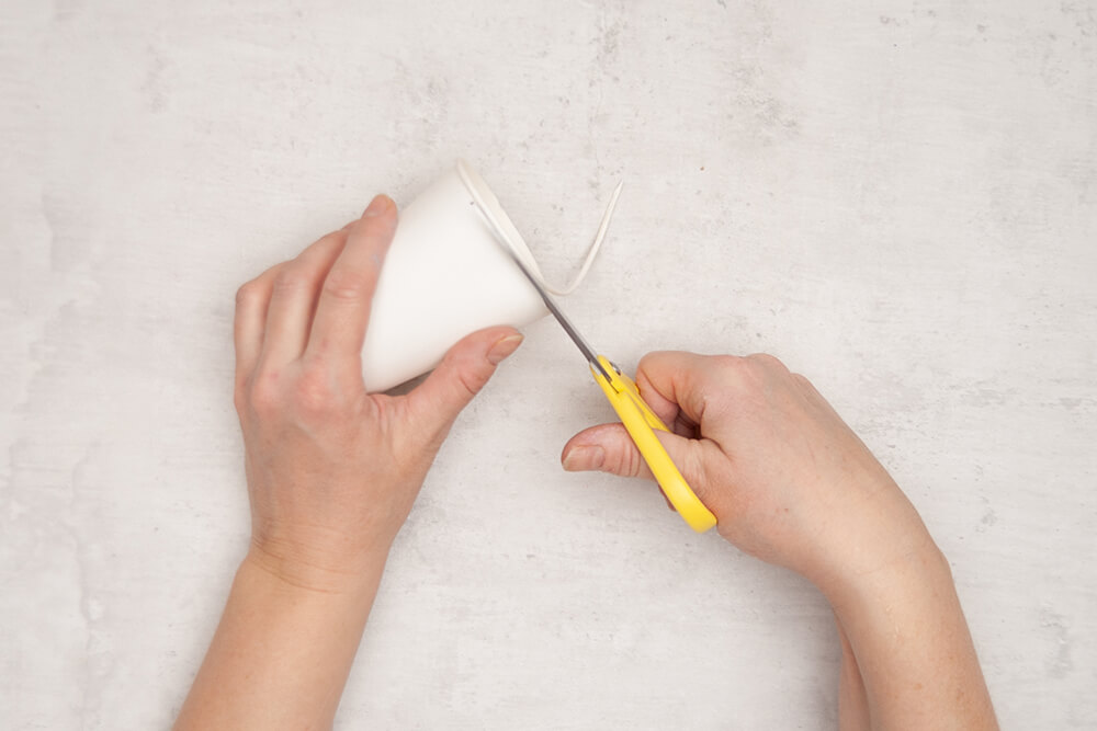 Der obere Rand eines Pappbechers wird rundherum mit einer Schere abgeschnitten. Fotos: Johanna Rundel