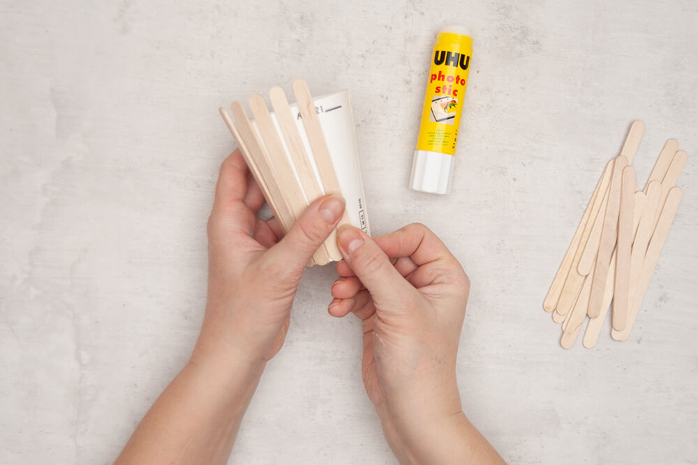 Um einen Pappbecher werden rundherum, in gleichmäßigem Abstand Bastelhölzer von Knorr-Prandell geklebt. Fotos: Johanna Rundel