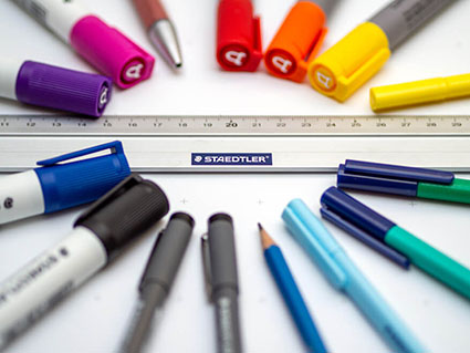 Auf einem Bogen Flipchart-Papier liegen verschiedene Stifte der Marke Staedtler, sowie ein Lineal.