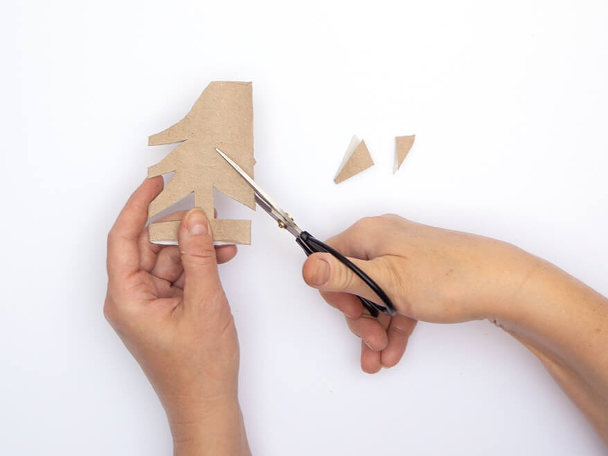 Jemand schneidet mit einer schwarzen Schere Zacken aus einer leeren Klopapierrolle. Der Untergrund ist weiß. Foto: Johanna Rundel