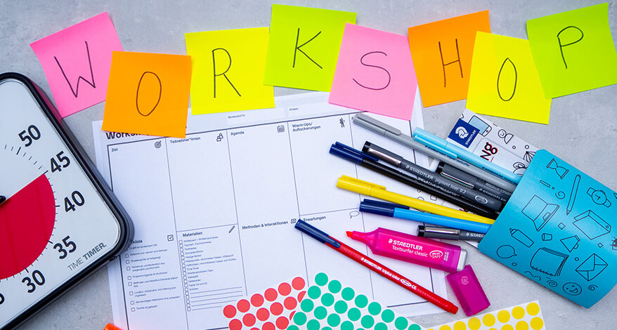 Verschiedene Materialien, die man zur Durchführung eines Workshops benötigt: Stifte und Marker von Staedtler, Klebepunkte, ein Time-Timer, Workshop-Canvas und Haftnotizzettel, auf denen "Workshop" steht. Foto: Johanna Rundel