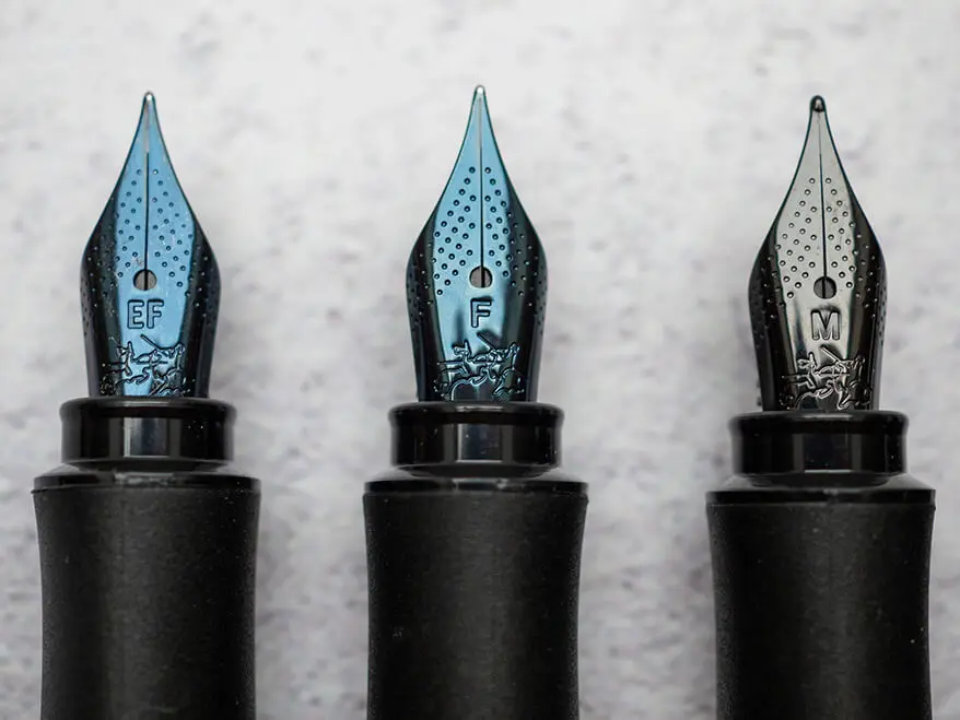 Drei schwarze Füllerspitzen von Faber Castell liegen auf einem hellgrauen Untergrund. Die verschiedenen Federstärken sind auf der Feder erkennbar (EF, F und M). Foto: Johanna Rundel